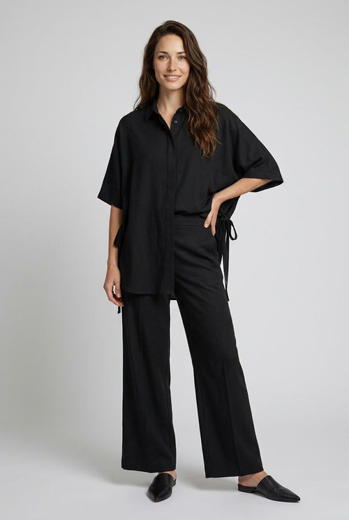 Casual Shirt with Stripe – full-length view of the black shirt showing the side tie detail, with wide-leg trousers and loafers