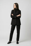 The Drift Ribbon Blazer – front view of the black blazer, model with arms crossed, worn with matching trousers