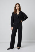 Cotton Jacket with Layered Ruffle – front view of the black V-neck cotton jacket, model with hand on hip, styled with black wide-leg trousers