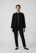 Wing Signature Jacket in black, full-length front view with central zip, worn with black trousers