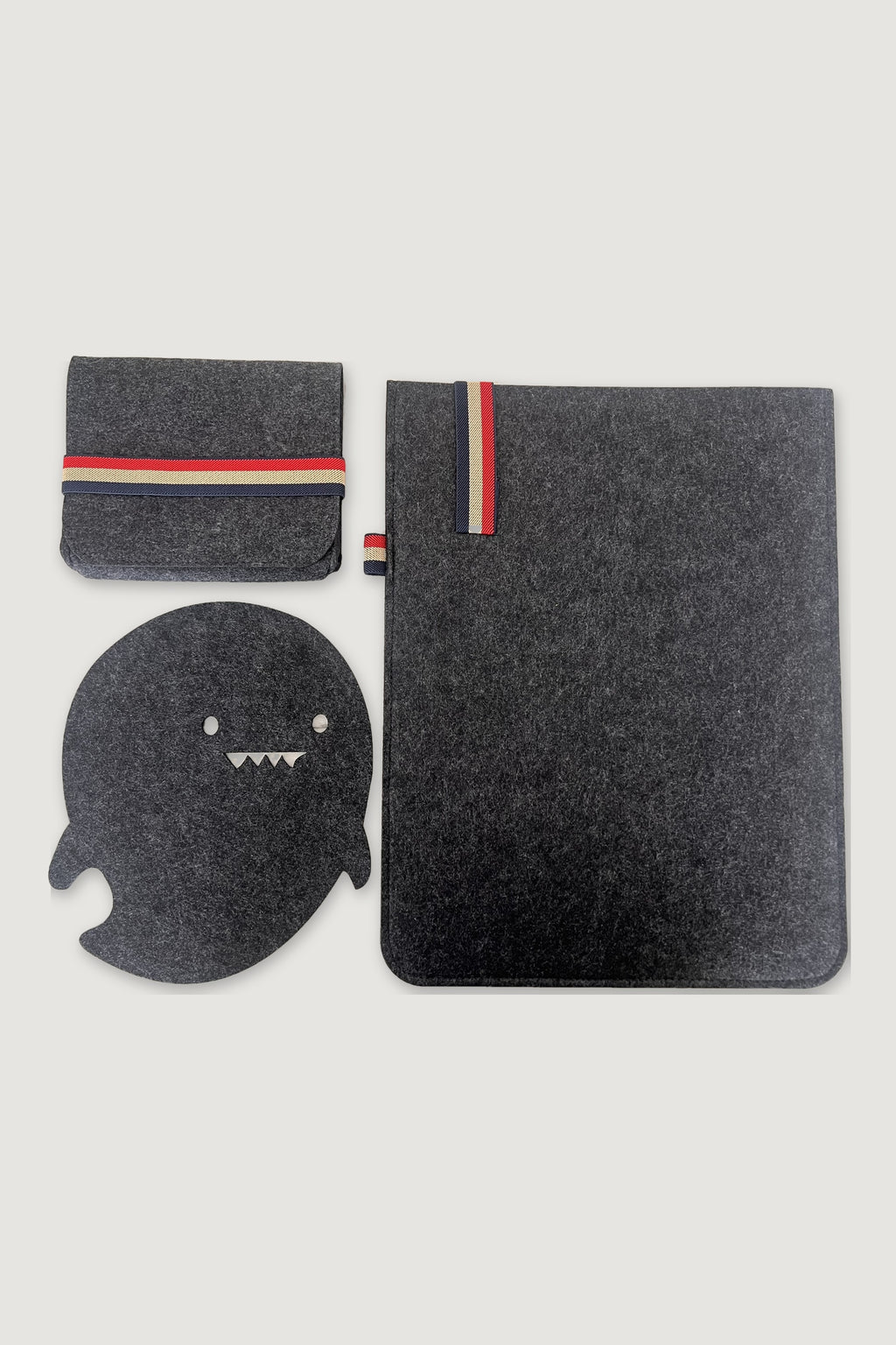Charcoal felt laptop sleeve set: laptop sleeve, organizer pouch with red, beige and navy striped elastic, and ghost-shaped mousepad, flat lay on light grey