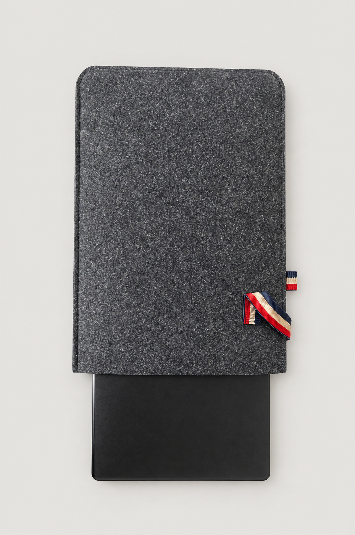 Laptop sliding out of the charcoal felt laptop sleeve with striped elastic tab (laptop not included)