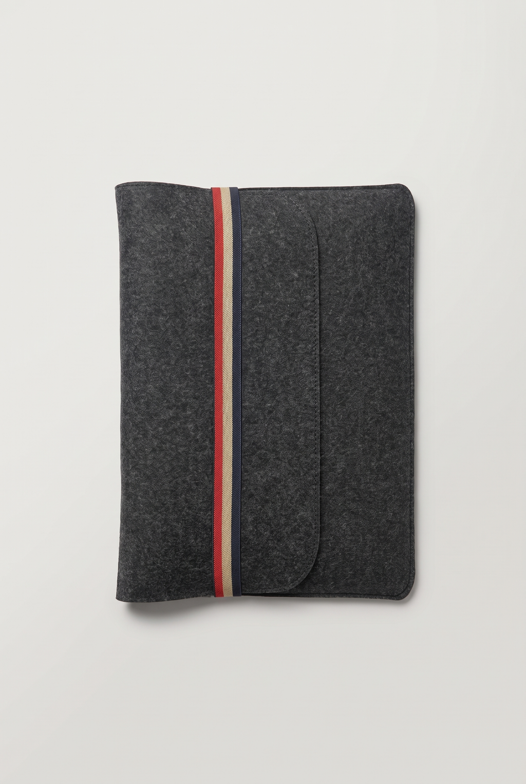 Closed charcoal felt laptop sleeve with cover, secured by a vertical red, beige and navy striped elastic band