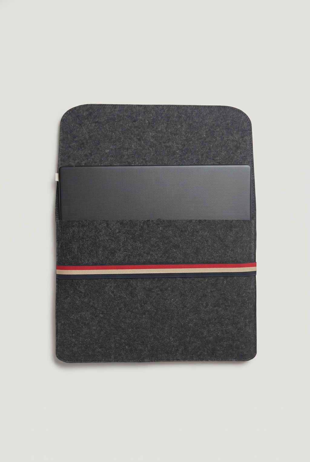 Laptop placed inside the open charcoal felt sleeve, ready to fold the cover and secure with the striped elastic band (laptop not included)